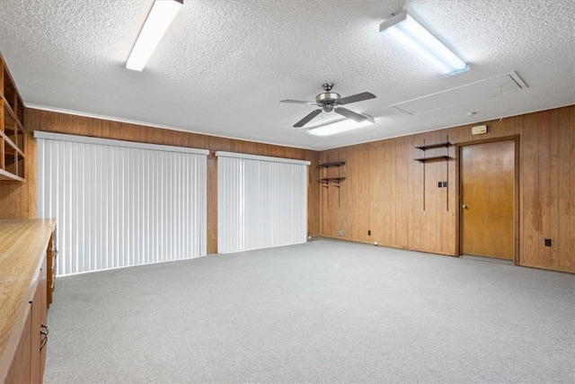 interior space featuring light carpet, a textured ceiling, ceiling fan, and wood walls