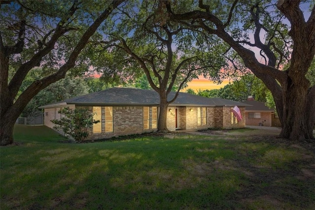 back house at dusk featuring a lawn