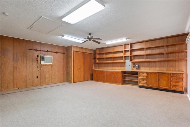 basement featuring a textured ceiling, an AC wall unit, ceiling fan, and wooden walls