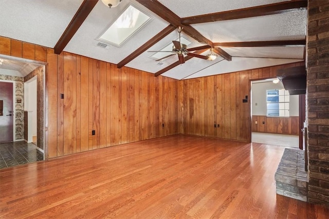 unfurnished living room with a textured ceiling, hardwood / wood-style flooring, and wooden walls