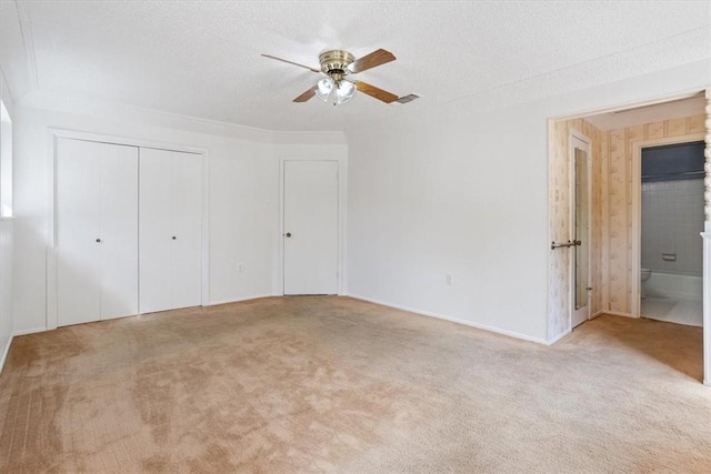 unfurnished bedroom with ceiling fan, light carpet, and a textured ceiling