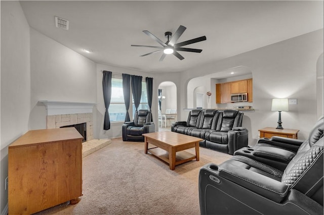 carpeted living room with ceiling fan and a fireplace