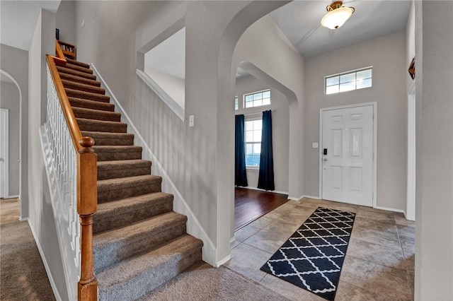 entryway featuring wood-type flooring and a towering ceiling