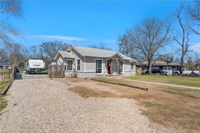 view of front of house featuring metal roof, fence, and driveway