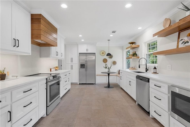 kitchen with sink, built in appliances, pendant lighting, white cabinets, and ornamental molding