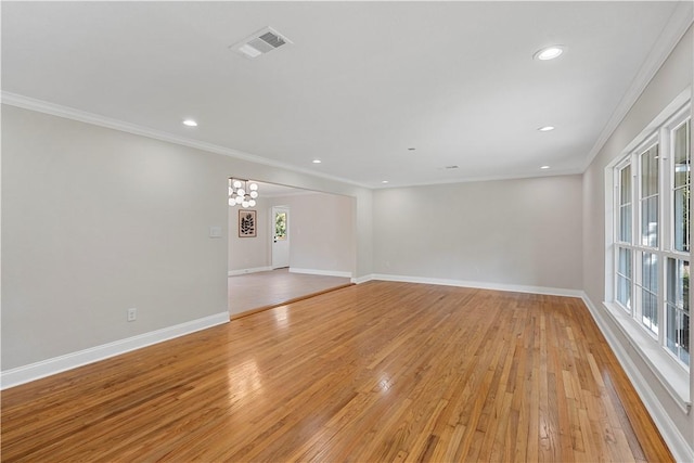 empty room featuring light hardwood / wood-style floors, crown molding, and an inviting chandelier