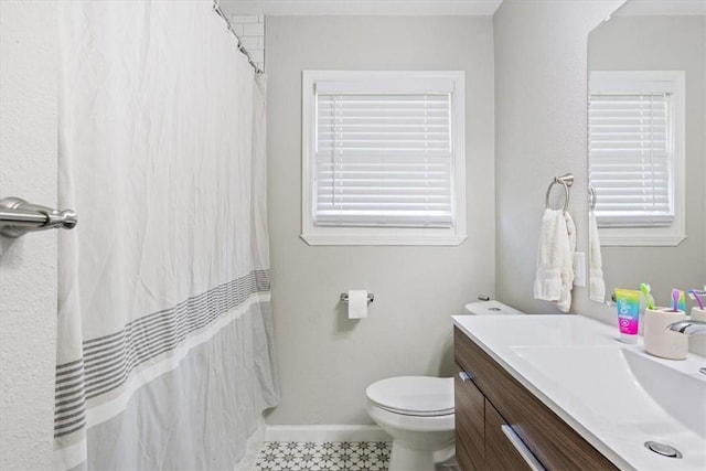 bathroom with vanity, curtained shower, toilet, and baseboards