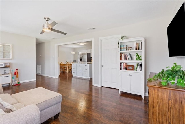 living area with visible vents, ceiling fan, baseboards, and wood finished floors