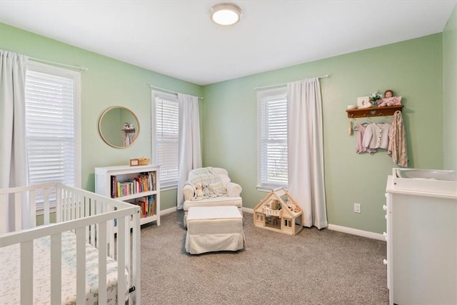 carpeted bedroom with a crib and baseboards