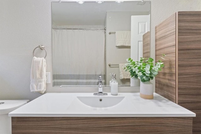 full bath featuring vanity and a textured wall