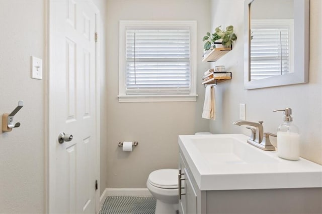 half bathroom with a wealth of natural light, baseboards, toilet, and vanity