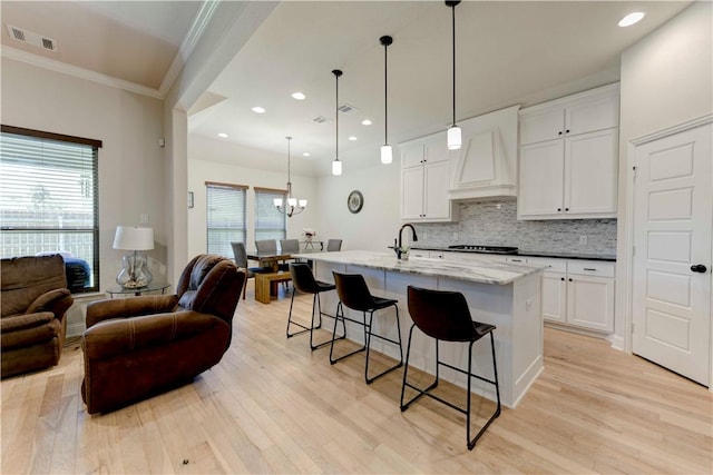 kitchen featuring premium range hood, a wealth of natural light, light hardwood / wood-style flooring, and white cabinetry