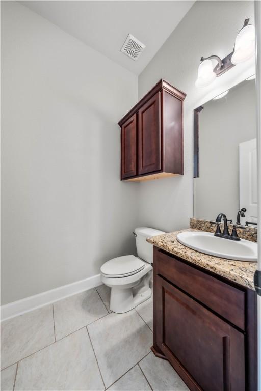 bathroom with toilet, vanity, and tile patterned floors