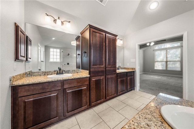 bathroom with tile patterned flooring, vanity, and vaulted ceiling