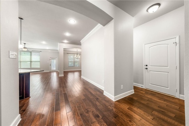 hallway with dark hardwood / wood-style flooring, an inviting chandelier, and crown molding