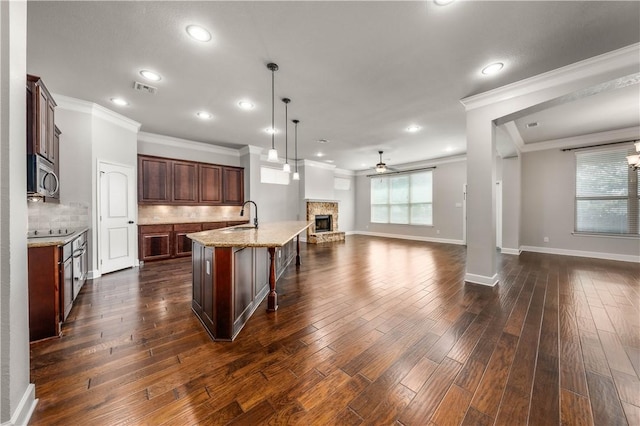 kitchen featuring ceiling fan, sink, hanging light fixtures, stainless steel appliances, and a center island with sink