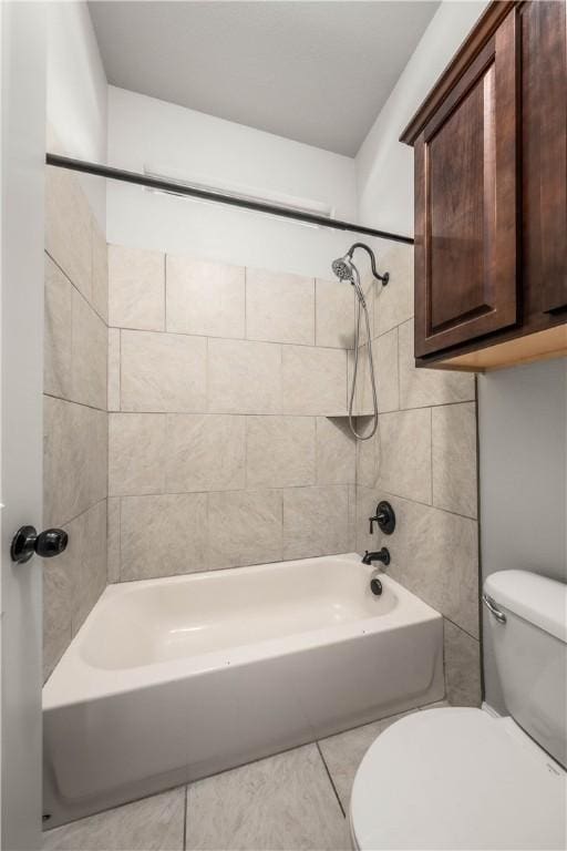 bathroom with tile patterned flooring, tiled shower / bath combo, and toilet