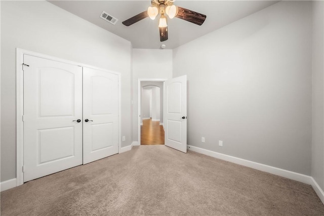 unfurnished bedroom featuring ceiling fan, light colored carpet, and a closet