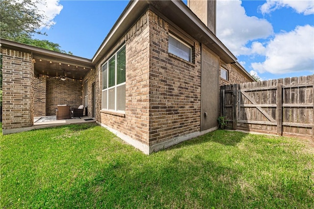 view of side of home with a yard and a patio