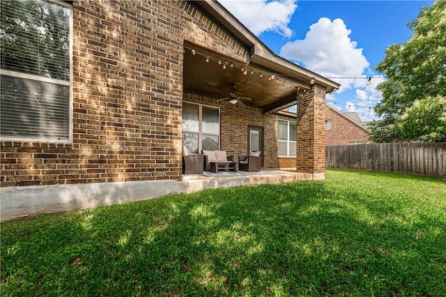 back of property with ceiling fan, a yard, and a patio