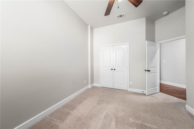 unfurnished bedroom with ceiling fan, light colored carpet, and a closet