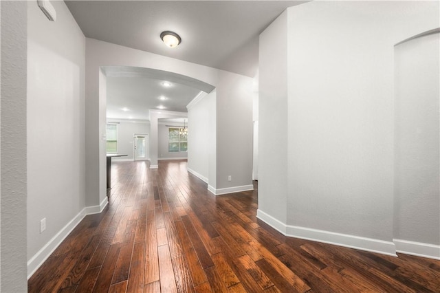 hallway with dark hardwood / wood-style flooring and a notable chandelier