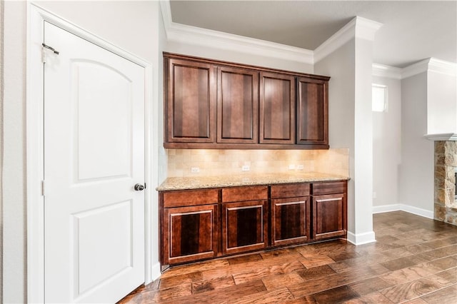 bar with backsplash, a fireplace, dark hardwood / wood-style flooring, and ornamental molding