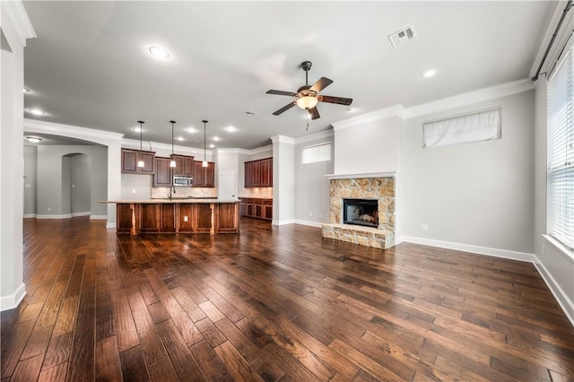 unfurnished living room with a fireplace, dark wood-type flooring, ceiling fan, and crown molding