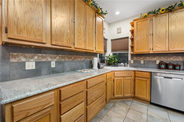 kitchen featuring dishwasher, sink, decorative backsplash, light stone countertops, and light tile patterned floors