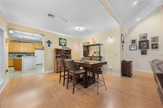 dining area with vaulted ceiling, light hardwood / wood-style flooring, and crown molding