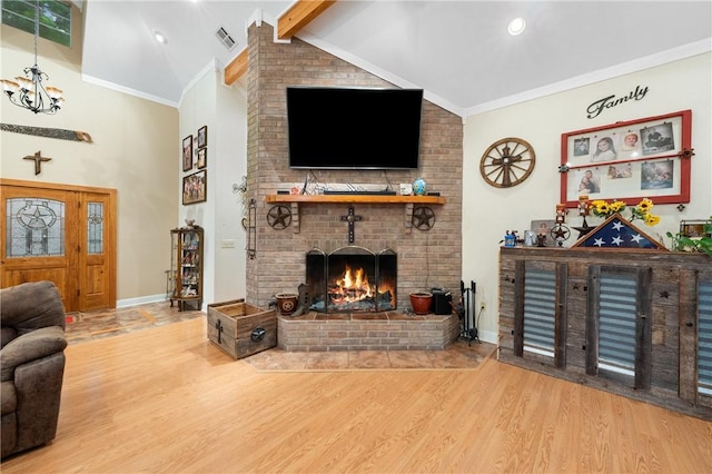 living room with crown molding, wood-type flooring, an inviting chandelier, a fireplace, and vaulted ceiling with beams