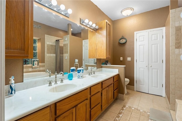 bathroom featuring toilet, a tile shower, vanity, and tile patterned floors