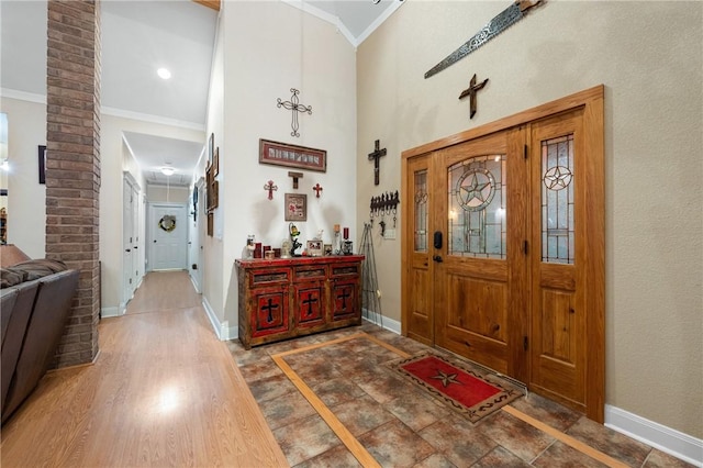 entrance foyer with a towering ceiling, dark hardwood / wood-style floors, and ornamental molding