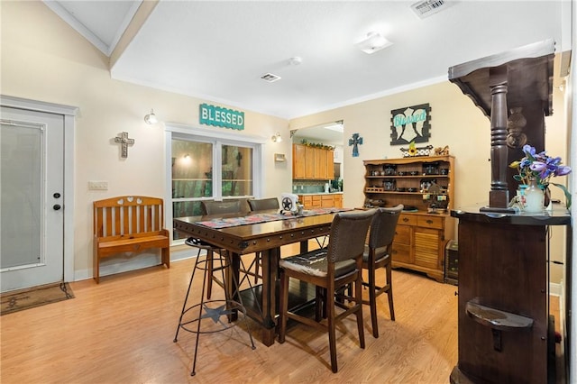 dining room featuring ornamental molding, vaulted ceiling, and light wood-type flooring