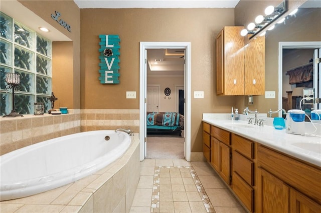 bathroom with tile patterned flooring, vanity, and tiled bath