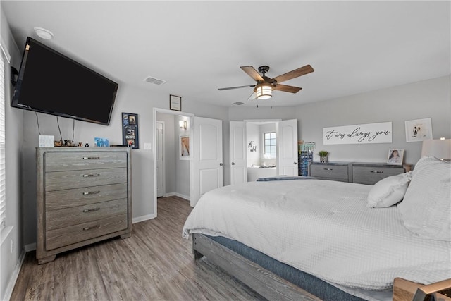 bedroom featuring connected bathroom, ceiling fan, and light hardwood / wood-style floors