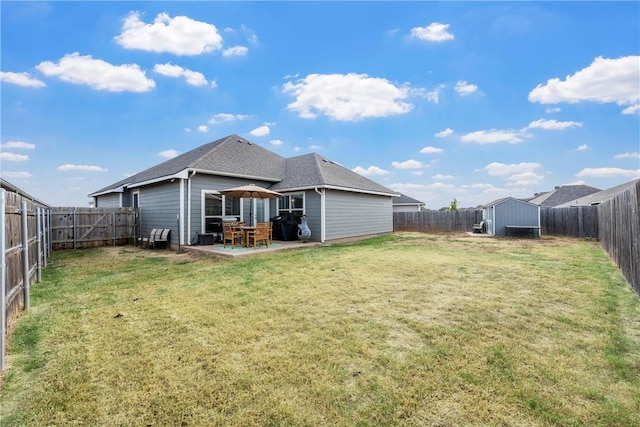 rear view of property featuring a lawn, a patio, and a storage unit