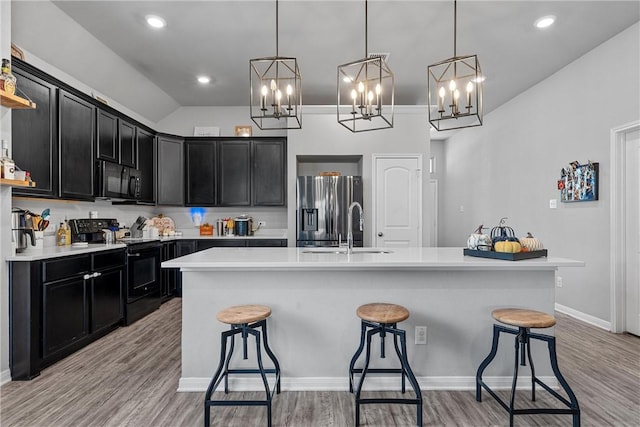 kitchen with black appliances, sink, a kitchen bar, and an island with sink