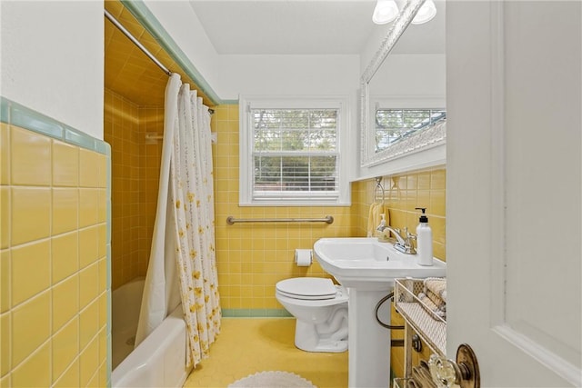 bathroom with toilet, shower / bath combo with shower curtain, and tile walls