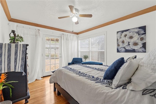 bedroom with a textured ceiling, ceiling fan, light wood-type flooring, and ornamental molding