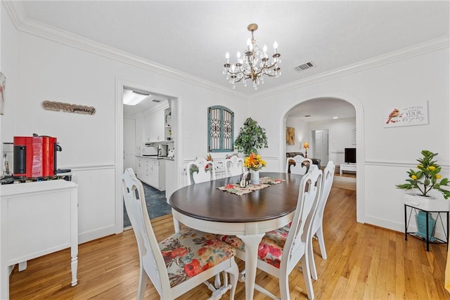 dining space featuring crown molding, a chandelier, and light wood-type flooring