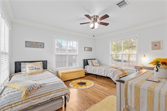 bedroom with hardwood / wood-style floors, multiple windows, ornamental molding, and ceiling fan