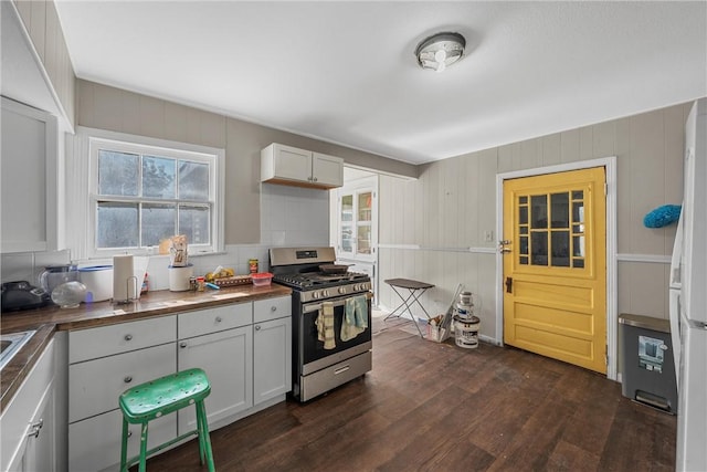 kitchen featuring white cabinets, stainless steel gas range oven, dark hardwood / wood-style flooring, and a wealth of natural light