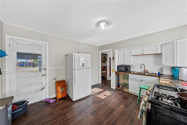 kitchen with white refrigerator, sink, dark hardwood / wood-style floors, white cabinetry, and stainless steel range with gas stovetop