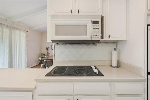 kitchen featuring black electric stovetop, white cabinetry, beamed ceiling, and tasteful backsplash