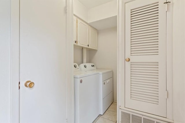 laundry room featuring cabinets, light tile patterned floors, and washing machine and clothes dryer