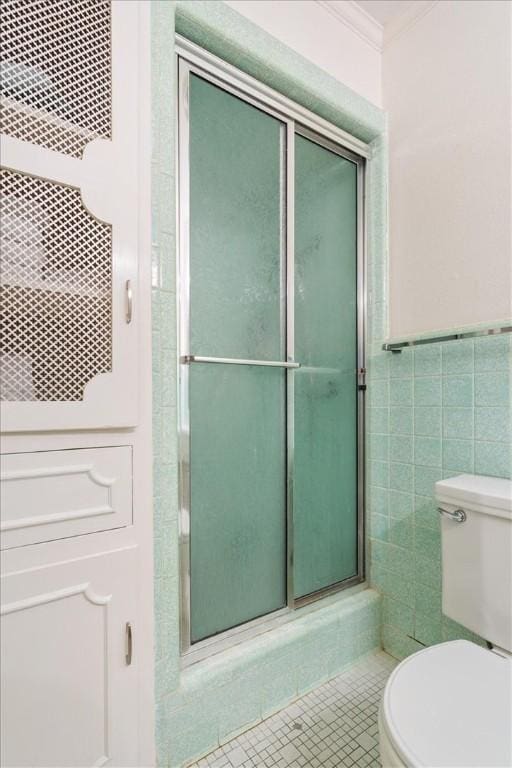 bathroom featuring walk in shower, ornamental molding, tile walls, tile patterned flooring, and toilet