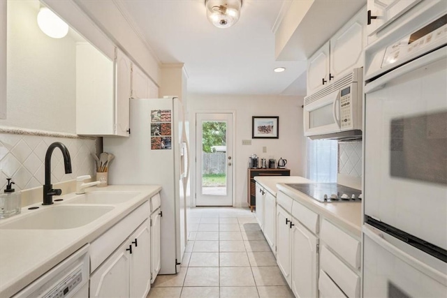 kitchen featuring tasteful backsplash, white appliances, sink, light tile patterned floors, and white cabinets