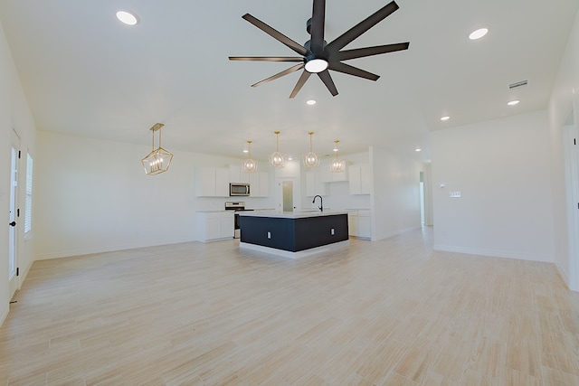 unfurnished living room with light hardwood / wood-style flooring, ceiling fan, and sink