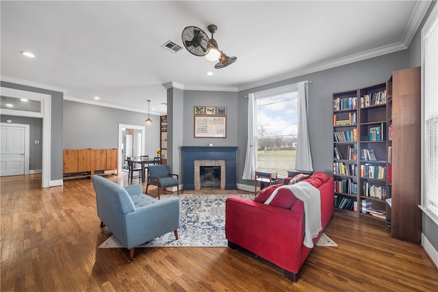 living room featuring visible vents, a fireplace, baseboards, and wood finished floors